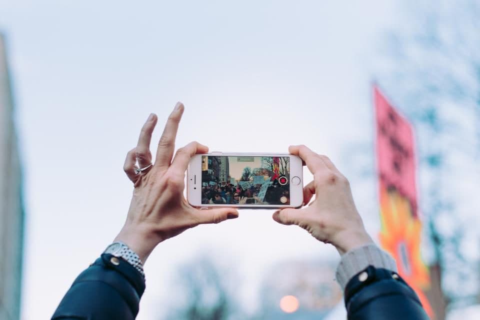 Hands holding up a phone to film a street festival