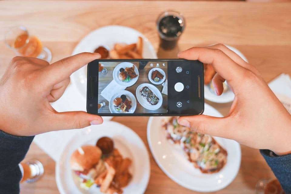 Someone photographing plates of food with a phone
