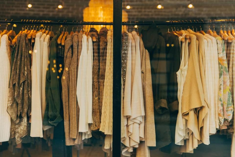 A rail of neutral-toned clothes in a boutique