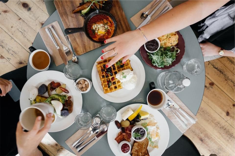 Friends sharing brunch plates on a round table, seen from above